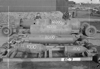 Armourers show off bombs for a comparison in size at the bomb dump at Woodhall Spa, Lincolnshire. In the front are 1,000-lb and 500-lb MC bombs, behind them a 2,000-lb HC Mark I, then a 4,000-lb HC Mark III or Mark IV 'Cookie'. Finally, at the rear, is a 12,000-lb HC 'Blockbuster', essentially three 4,000-lb 'Cookies' bolted together with the addition of a six-finned ballistic tail.